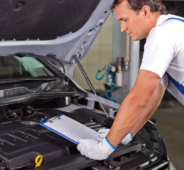 Man står i en bilverkstad vid en bil med öppen motorhuv