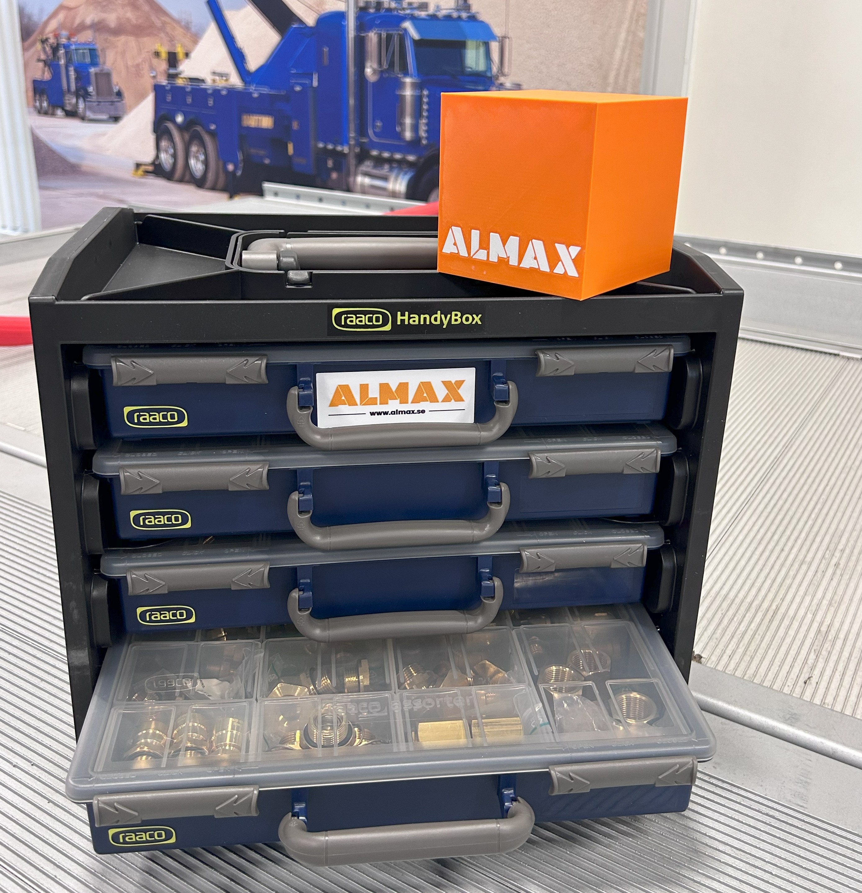 raaco handybox med sortimentslåder. En orange kube med ALMAX står ovanpå